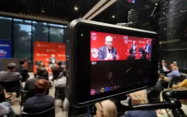 A conference session filmed from the back of the room