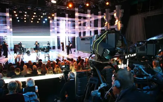 Cameras covering a live event on a lit stage